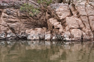 Huzurlu doğa manzarası, sakin sulardaki kayalıkların yansıması pürüzsüz kaya dokusuyla sakin nehir manzarasını ve sakin açık hava ortamını gösteriyor.