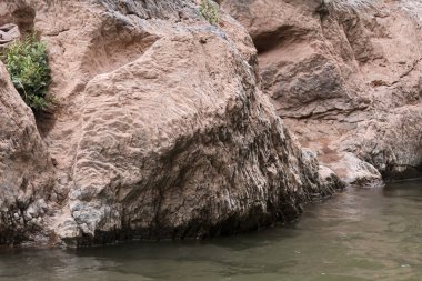 Sert dokulu yüzeyi ve derin gölgesi vahşi doğada dinginliği ve huzuru yansıtan engebeli, kırmızımsı taş oluşumu.
