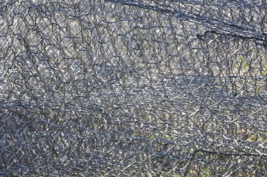 Bükülmüş kümes telinin soyut gri metal dokusu endüstriyel ızgara desenini ve geometrik altıgen delikleriyle korunmayı gösteren tel örgüleri gösteriyor.