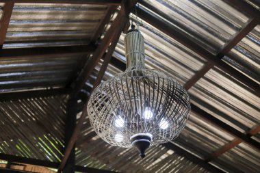 Parlak ampullü taşralı lamba, klasik tavan içini aydınlatıyor. Geleneksel kahve dükkanında, barışçıl nostaljik ruh haliyle sıcak ve rahat bir atmosfer yaratıyor.