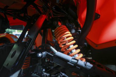 Turuncu şok emici yay detayı görüntüsü güçlü ağır görev araç şasesi altında mekanik ulaşım sisteminde güç ve dayanıklılık gösteriyor