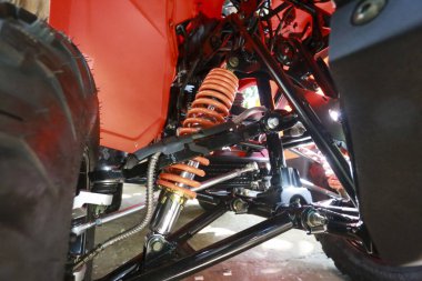 Güçlü off-road aracının ön süspansiyonu turuncu şok emici yay ve siyah lastik izi mekanik detayları ve zorlu arazi macerası için mühendislik tasarımını gösteriyor.