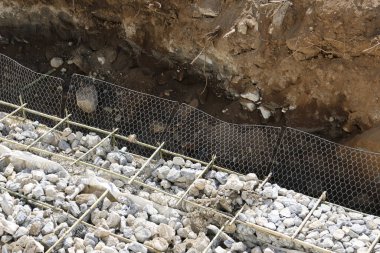 İnşaat alanı temelleri ezilmiş taş, çelik destek çubuğu örgüsü ve toprak hendeği endüstriyel ilerlemeyi ve zeminde yapısal istikrar çalışmalarını gösteriyor.