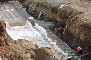 Beton takviyeli ve beyaz kum torbası koruma duvarlı büyük kazı hendeği inşaatı endüstriyel gelişimi gösteriyor.