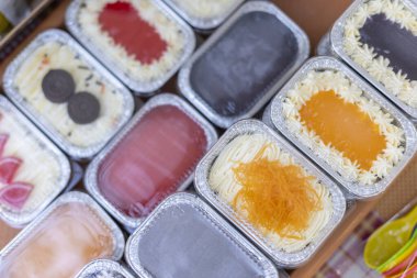 Renkli alüminyum folyo kutusuyla çeşitli lezzetli pastalar çeşitli lezzet çeşitlerini gösteren arka plan pasta dükkanındaki tatlı aşıkları için mutlu ve lezzetli duygular yaratıyor.