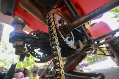 Güçlü metal sürücü zinciri, çelik çıkıntı ve güçlü kırmızı off-road aracı veya mekanik gücü, kuvveti vurgulayan dört tekerlekli bisikletin altında ağır çekiş halatını gösteren yakın görüş