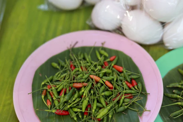 Taze yeşil ve kırmızı biber muz yaprağı tepside tuzlu yumurta arka planında lezzetli Tayland yemeği pişirmeye hazır baharatlı içeriği gösteriyor.