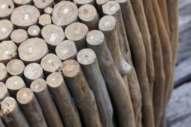 Kırsal ahşap tabureye yakın görünüm. Yığılmış ağaç dalları kaba desenli ve yıpranmış kahverengi yüzey, bahçedeki doğal yaşı ve ayrıntıları gösteriyor.