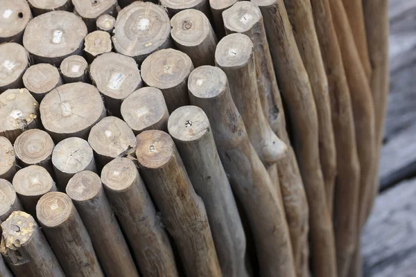 Kırsal ahşap tabureye yakın görünüm. Yığılmış ağaç dalları kaba desenli ve yıpranmış kahverengi yüzey, bahçedeki doğal yaşı ve ayrıntıları gösteriyor.