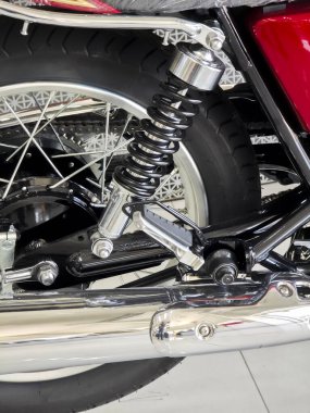 Parlak krom detaylar gösteren klasik kırmızı motosikletin arka süspansiyonunu kapat artı güçlü makine mühendisliği güçlü maceracı tasarım konseptiyle özgürlük ruhunu vurguluyor.