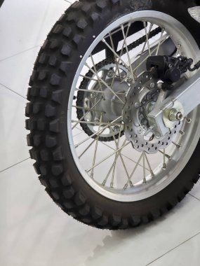 Güçlü motorsikletin sağlam arka tekerleği dayanıklı metaldeki sert lastik izleri garajın içindeki sergi salonunun beyaz fayans zemininde yoğun bir off-road macerası olduğunu gösteriyor.