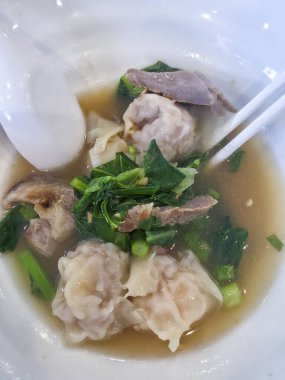 Lezzetli Çin mantısı çorba kasesi, lezzetli et suyu, dilimlenmiş domuz eti, taze yeşil sebze, hamur köftesi ve çubuk Asya yemek kültürü için lezzetli ve rahatlatıcı görünüyor.