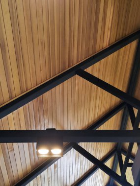 Modern ahşap tavan, siyah metal kiriş kiriş yapısı ve sıcak aydınlatma lambası rahat endüstriyel çatı katı atmosferi yaratıyor ve iç mimari için rahatlatıcı bir ortam yaratıyor.