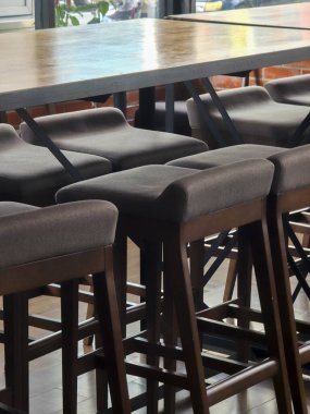 Modern endüstriyel çatı katı tarzı kafe restoranının içinde kahverengi deri taburesi olan boş, uzun, ahşap masa dinlenmek ve çalışmak için sakin bir atmosfer sağlıyor.