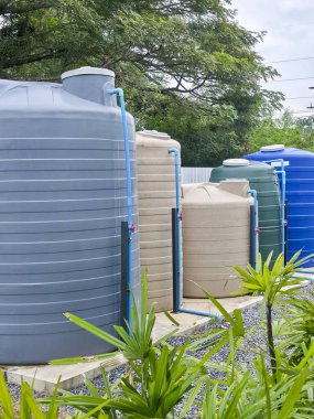 Birkaç büyük plastik su tankı tarımsal depolama için açık alanda duruyor pratik yararlı sürdürülebilir kaynak yönetimi sakin yeşil çevre