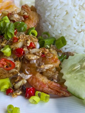 Kızarmış karides, tuzlu biberli ve sarımsaklı ve buğulanmış pirinçli beyaz tabak iştah açıcı ve restoranda öğle yemeği için geleneksel Tayland yemeği menüsü sunuyor.