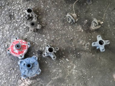 Paslı eski araba parçaları mekanik dişliler ve metal parçaları garajın kirli beton zemininde yağlı desenli bir atölyede yatıyor.