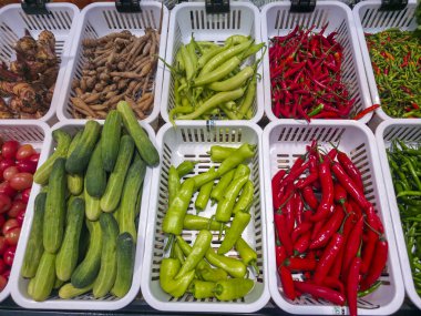 Taze sebze tezgahı organik biber, salatalık ve zencefil kökü beyaz plastik sepet satarak sağlıklı besin içeriği çeşitliliği ve renkli ham baharat seçimi sunuyor.