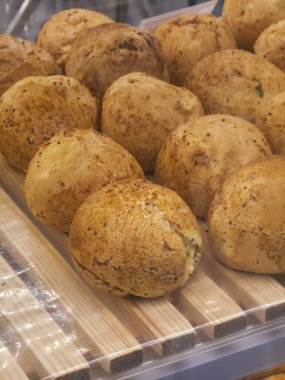 Kahverengi ekmekli çörek ahşap rafta fırın vitrininde. Kahvaltıda taze kepekli hamur işi ve iştah açıcı bir hava ve leziz bir doku var.