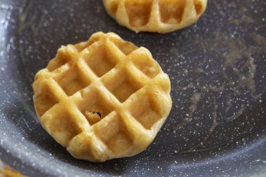 Yapışkan olmayan sıcak tavada pişirilmiş altın mini waffle, yumuşak bir kahvaltı için hazır. Sabah mutfağında sıcak ev yapımı konforlu yemek hissi veriyor.
