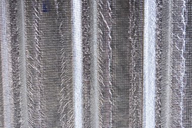 Gümüş metalik yalıtım folyo malzemesinin dokusu dikey çıkıntılar ile kapanıyor. Sıcaklığı kontrol altına almak için sağlam endüstriyel yüzeyi gösteren çatı arkası konsepti.