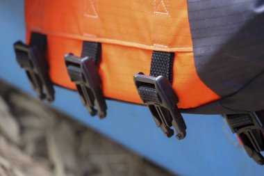 Sağlam siyah plastik toka ve dayanıklı kayış sistemi içeren turuncu su geçirmez çantanın yakın görüntüsü. Güvenli ve sağlam bir şekilde güvenli bir şekilde dışarı çıkmak için sağlam ve dayanıklı araç gereçler.