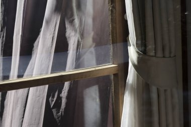 Ürkütücü pencere manzarası ahşap çerçeveli ve perdeli perdeli korkunç kumaş bantlarına bakıyor mumya gibi asılı korku esrarı ve gerilim titreşimleri uyandırıyor eski perdeli evde.