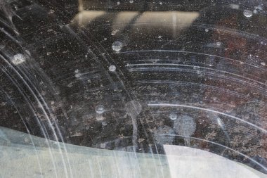 Eski vinil plak yüzeyinin çizilmiş dokusu dairesel oyuk ve dağınık toz lekeleri retro grunge soyut arka plan deseni ve müzikal nostaljiyi gösteriyor.