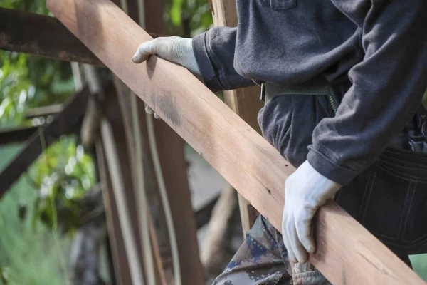 Usta marangozlar ağır ahşap kalaslar taşıyorlar. İnşaat sırasında çok dikkatli tutuyorlar. Koruyucu eldivenler giyiyorlar.