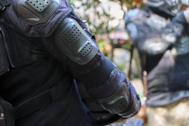 Siyah motosikletli koruyucu ceketin detaylı yakın çekimi dirsek koruyucusu kolunun emniyet duruşu ve güvenli motosiklet macerası için hazır olduğunu gösteriyor.