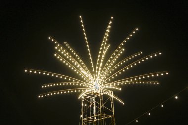 Güzel, parıldayan yıldız patlaması tesisi karanlık gece gökyüzünde parlıyor. Neşeli ve bayram kutlamalarıyla dolu büyülü bir festival atmosferi yaratıyor.