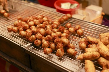 Lezzetli ızgara Tayland usulü mayalanmış domuz sosisi. Metal tel askıda pişirilmiş, nefis aroması ve geleneksel sokak yemeği kültürünü temsil eden altın kahverengi deri dokusu olan.