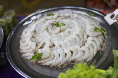 Çiğ kabuklu beyaz karides, metal tepside taze dairesel desenli ve lezzetli görünüyor. Lezzetli yemek için hazır. Yerel deniz ürünleri lokantasında sağlıklı malzemelerle birlikte.