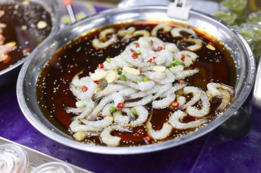 Baharatlı biber soslu taze çiğ karides ve market tezgahındaki metal tepside sarımsak. Aç müşteriyi lezzetli Tayland deniz ürünleri yemeye davet ediyor.