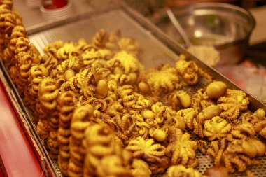 Lezzetli ızgara ahtapot ve metal tepside kalamar şişleri iştah açıcı ve lezzetli sokak yemekleri sunuyor altın kahverengi desenli ve gece pazarındaki aç müşteriler için lezzetli aromalı.