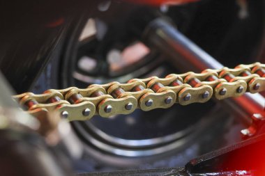 Yakın çekim makro çekim parlak altın rengi motorsiklet zinciri zinciri güçlü endüstriyel mekanik parçalarla bağlantılı koyu bulanık arka planda