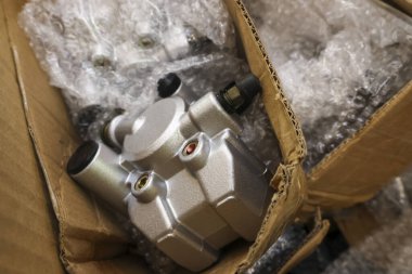 Yeni gümüş otomotiv parçası güvenli bir şekilde karton kutunun içine yerleştirildi. Koruyucu plastik baloncuk ambalajı acil onarım için bekleyen müşteriye gönderilmek üzere hazır.