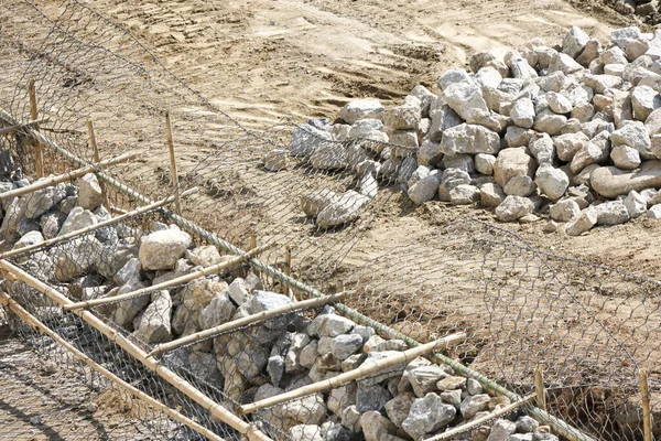 İnşaat sahasında, ahşap iskeletin içindeki hammadde yığını ve taş yığınının, eksik gelişimi ve pürüzlü dış dokuyu gösteren dağınık zemin üzerindeki yapı çalışması