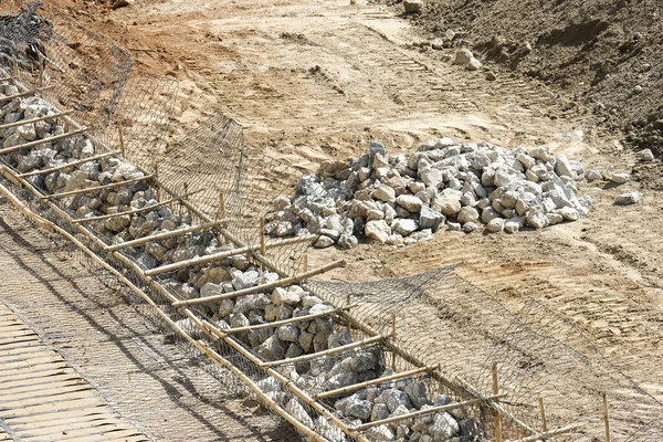 Metal inşaat demirinin içindeki sert taş malzemelerle birlikte inşaat alanı. Çerçeve yapısı, kuru kahverengi toprak zemini. Ağır endüstriyel mühendisliği gösteren inşaat alanı.