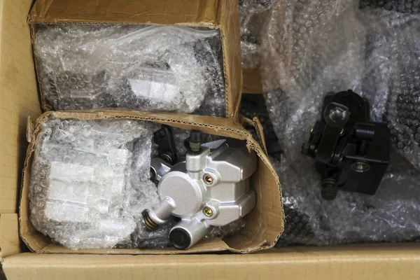 Otomotiv yedek parçasının güvenli bir şekilde teslim edilmesi için koruyucu baloncuklu paket kutusunun üst görüntüsü. Metal fren kalibreli dikkatli hazırlanma ve organize lojistik dağıtımı gibi.