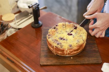 Ev yapımı lezzetli meyveli keki ya da ahşap masaya konmuş peynirli keki fırın kafeteryasının mutfağında tatlı tatlılı pasta servisi yaparken gösteren yakın bir manzara.