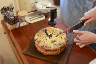 Mutlu insan eli ahşap masada tatlı yaban mersinli pasta keserken, pastanede bıçakla ev yapımı tatlı diliminin keyfini çıkarırken aile ile kutlama partisi.