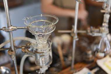 Kafeterya ortamında siyah espresso hazırlayan cam kahve makinesinin yakın plan çekimi, kafein içecek servisi için konsantrasyon ve temiz steril laboratuvar tarzı hazırlık sürecini gösteriyor.