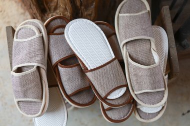Rahat bej kumaş ev terlikleri ahşap bir kutuda konforlu otel konukseverliği ve misafir konforu servisi için spa ayakkabıları.