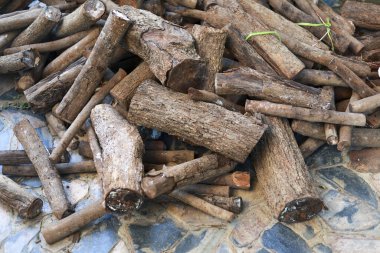 Taş zemine istiflenmiş kuru kahverengi odun ve kereste yığını soğuk kış mevsiminde şenlik ateşine ya da kamp ateşine hazır kırsal doku ve atmosfer yaratıyor.