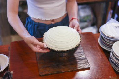 Mutlu genç fırıncı kadın ahşap masada güzel hindistancevizli kek sunuyor tatlı kutlama partisine hazırlanıyor ev yapımı fırın mutfağı eğlenceli.