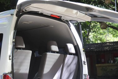 Açık beyaz minibüs arka kapısı. Geniş gri koltukları sergiliyor. Macera seyahatine ya da aile tatili yolculuğuna hazır.