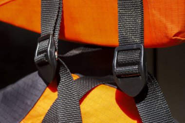 Kapalı görünüm parlak turuncu kumaş güvenlik yeleği ile dayanıklı siyah kayış ve korunmak için plastik toka ve hayatta kalma vitesi konseptini gösteren doku detaylarını gösterir