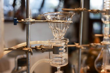 Yavaş damlama metodu için kullanılan karışık tüpler ve damlayan huni ile berrak bilimsel camdan yapılmış soğuk kahve kahve kulesinin yakın çekimi barista için rahatlatıcı atmosfer kafe laboratuvarı oluşturur.