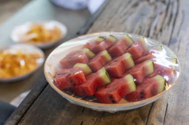 Taze kırmızı dilimlenmiş karpuz meyvesi, yaz diyeti için sağlıklı atıştırmalıklar, kırsal ahşap masada oturur, serin, lezzetli bir his uyandırır.